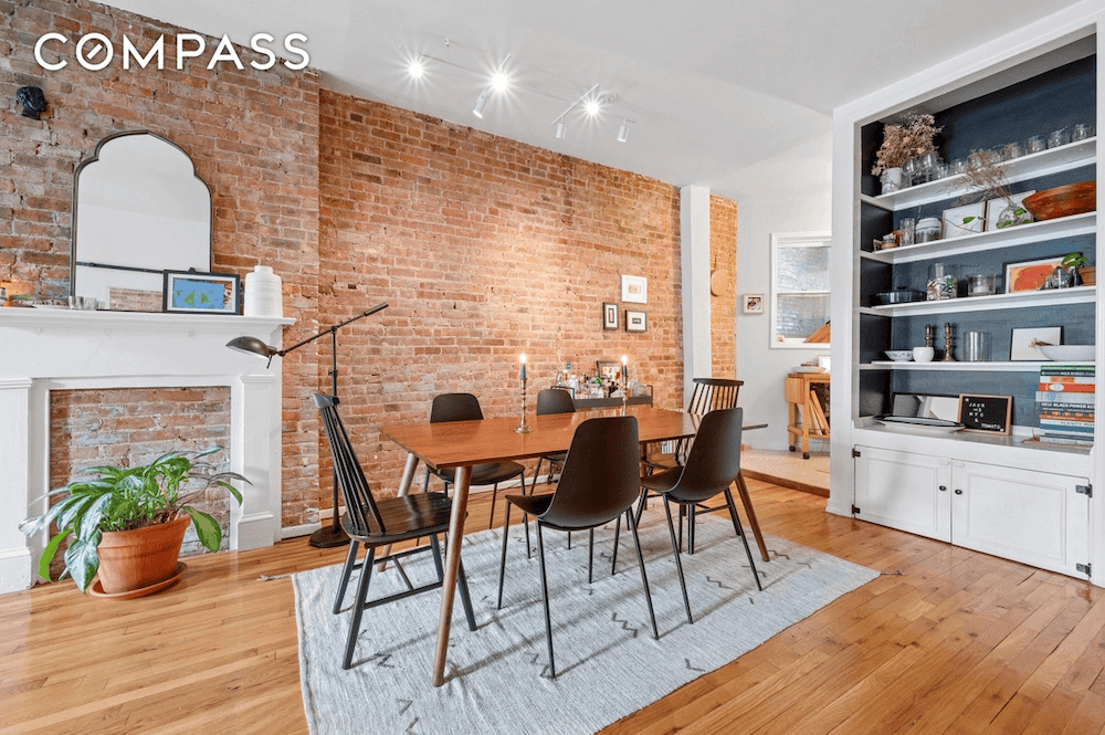 Manhattan living room with exposed brick, decorative fireplace, and bookshelf